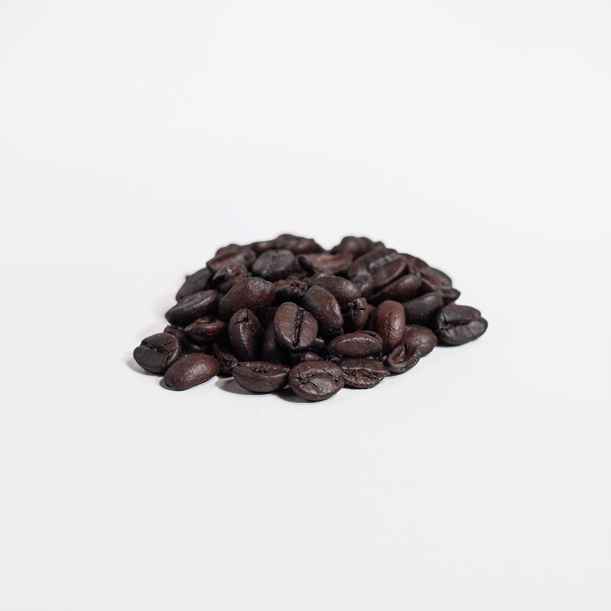 Close-up of dark roasted single-origin Brazilian Blend coffee beans scattered on surface